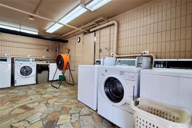 laundry room with washer and clothes dryer and tile walls