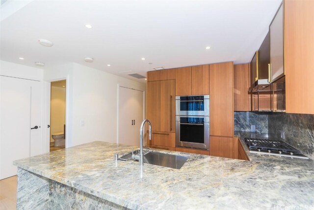 kitchen with sink, decorative backsplash, light hardwood / wood-style floors, light stone counters, and stainless steel appliances