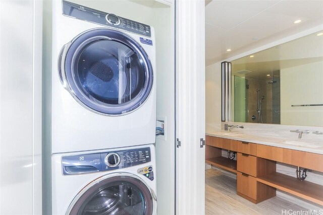 washroom with light wood-type flooring, stacked washer / drying machine, and sink