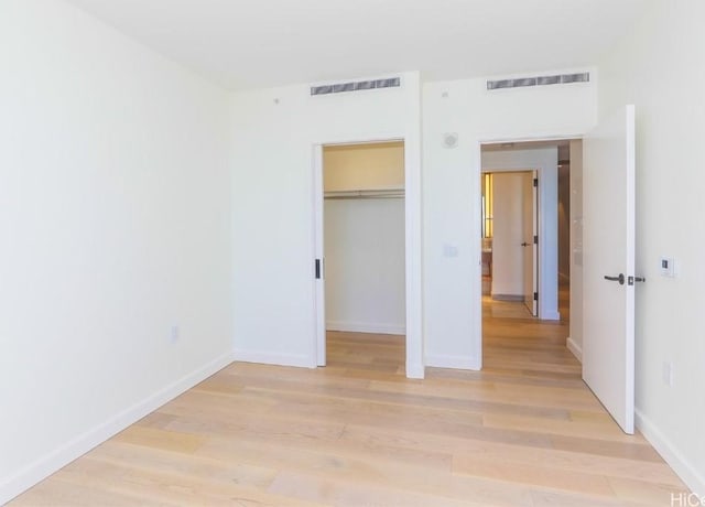 unfurnished bedroom with a spacious closet, light hardwood / wood-style floors, and a closet