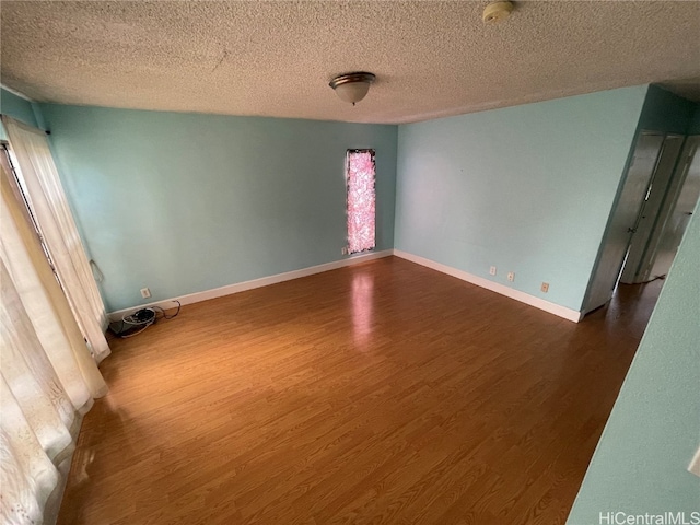 unfurnished room featuring a textured ceiling and dark hardwood / wood-style floors