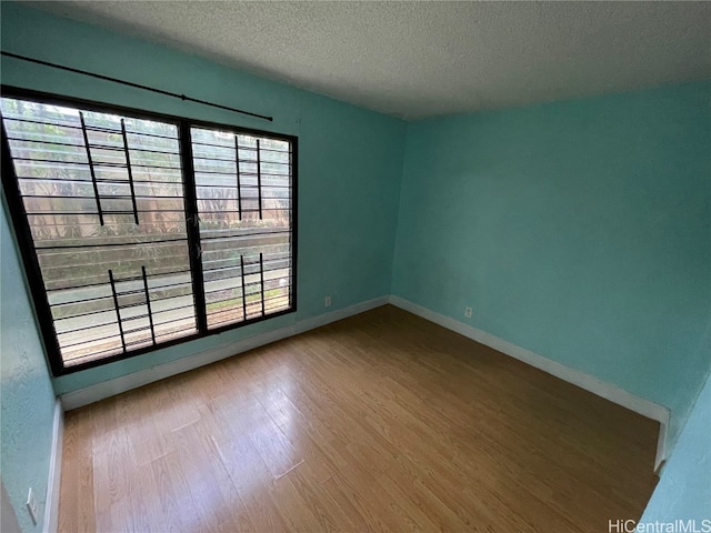 unfurnished room with wood-type flooring and a textured ceiling