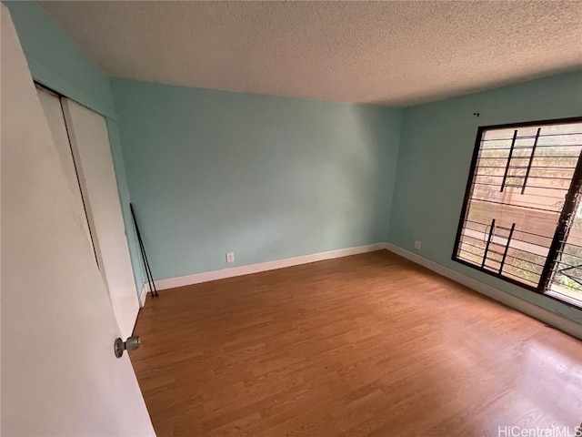 empty room featuring wood-type flooring and a textured ceiling