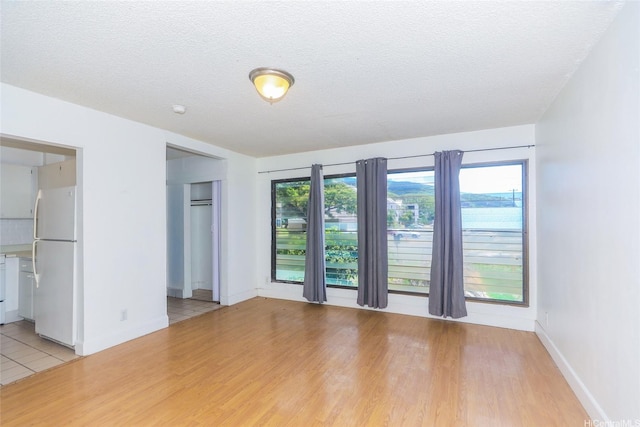 87-118 Helelua St Unit B101, Waianae, HI 96792 - unfurnished living room with baseboards, light wood-style floors, and a textured ceiling