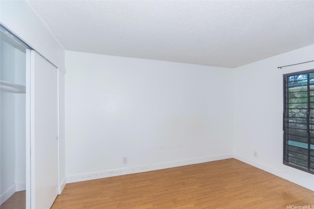 87-118 Helelua St Unit B101, Waianae, HI 96792 - unfurnished bedroom featuring a closet, light wood-type flooring, baseboards, and a textured ceiling