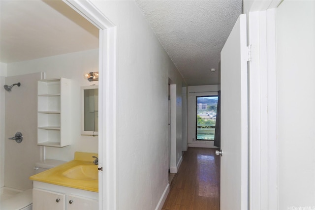 87-118 Helelua St Unit B101, Waianae, HI 96792 - hallway with a textured ceiling, wood finished floors, baseboards, and a sink