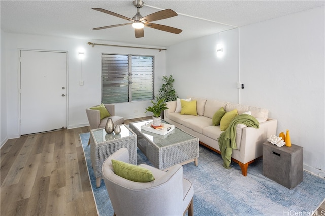 living room with ceiling fan, a textured ceiling, and hardwood / wood-style flooring