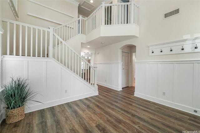 91-1038 Kaihohonu St, Ewa Beach, HI 96706 - staircase with a decorative wall, arched walkways, wood finished floors, a wainscoted wall, and a towering ceiling
