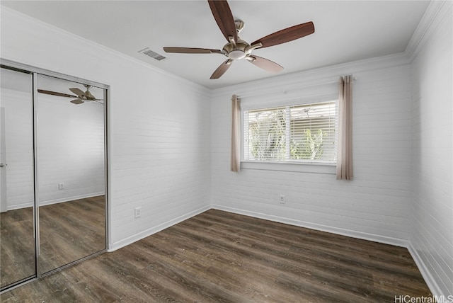 unfurnished bedroom featuring crown molding, dark hardwood / wood-style floors, ceiling fan, and a closet