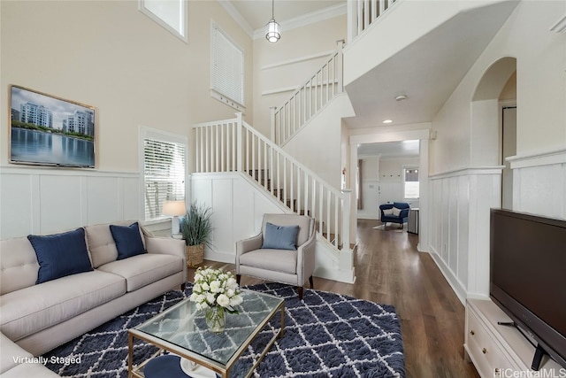 living room with a high ceiling, crown molding, and dark wood-type flooring