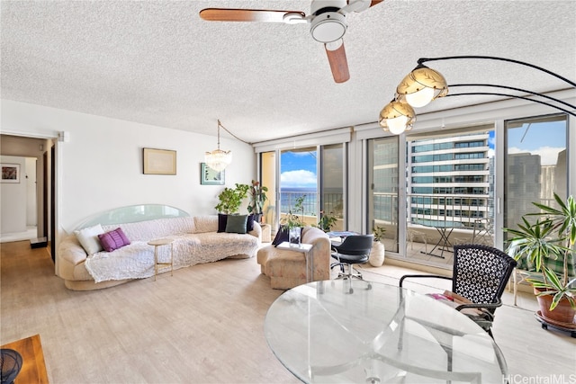 living room with light wood-type flooring, a textured ceiling, plenty of natural light, and ceiling fan