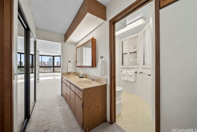 bathroom featuring tile patterned floors, vanity, toilet, and a textured ceiling