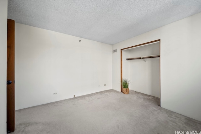 unfurnished bedroom featuring light carpet, a closet, and a textured ceiling