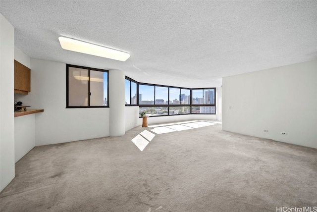 unfurnished living room featuring a textured ceiling and light carpet