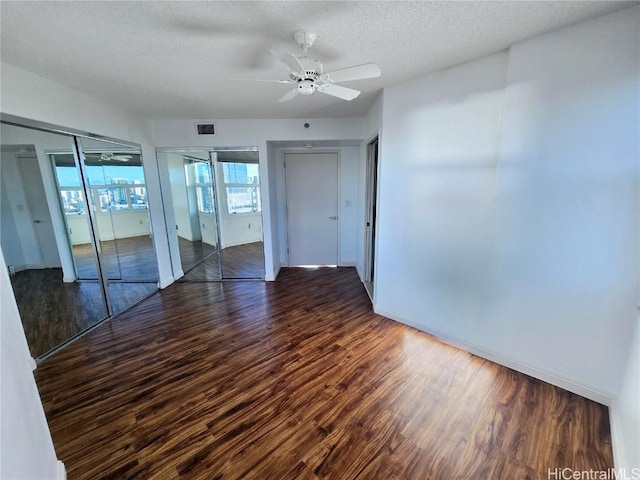 empty room with a textured ceiling, ceiling fan, and dark wood-type flooring