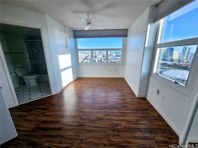 empty room featuring a textured ceiling, dark hardwood / wood-style flooring, and ceiling fan