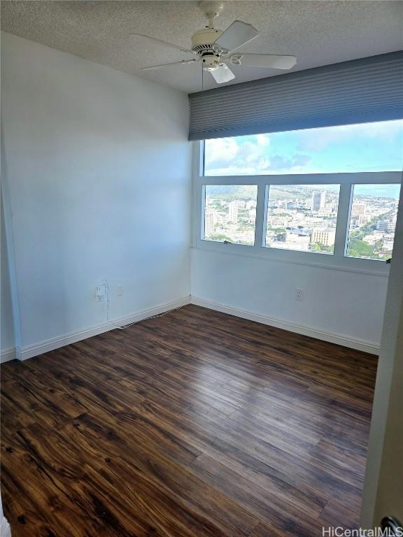 unfurnished room featuring a textured ceiling, dark hardwood / wood-style floors, and ceiling fan