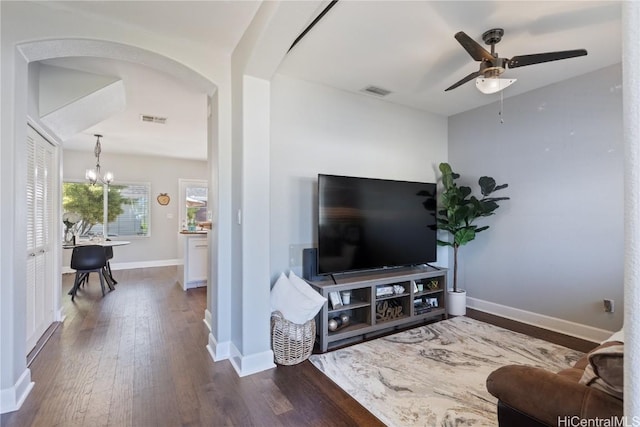 living room featuring ceiling fan with notable chandelier and dark hardwood / wood-style floors