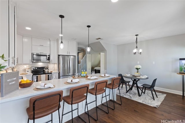 kitchen with stainless steel appliances, an inviting chandelier, backsplash, decorative light fixtures, and white cabinets