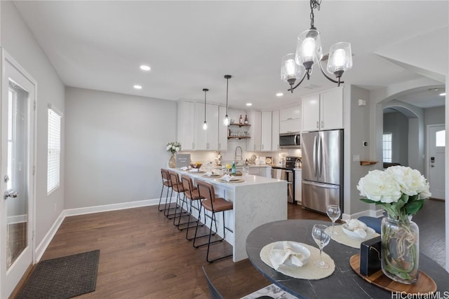 kitchen with hanging light fixtures, an inviting chandelier, decorative backsplash, white cabinets, and appliances with stainless steel finishes