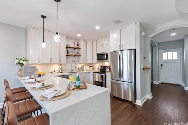 kitchen featuring appliances with stainless steel finishes, decorative light fixtures, white cabinetry, and sink