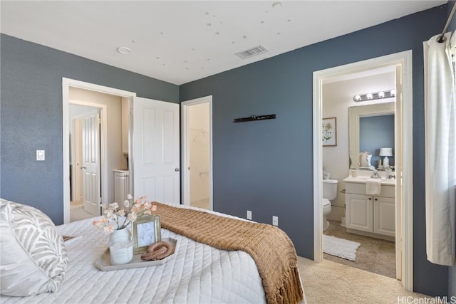 bedroom featuring ensuite bath and light colored carpet