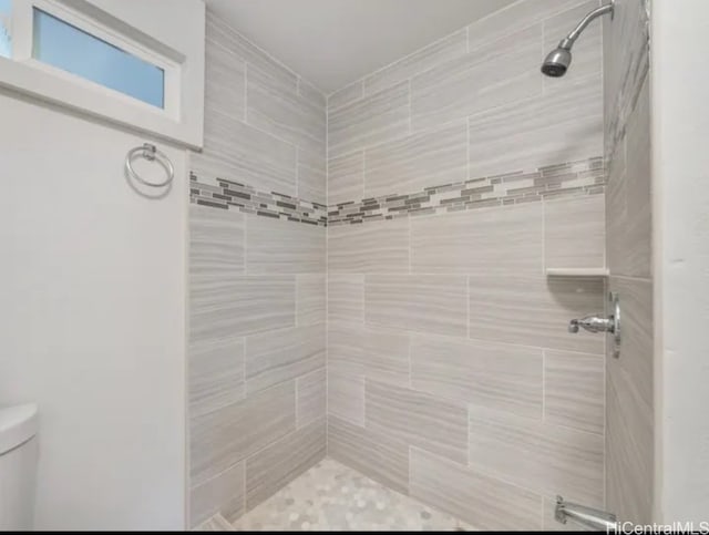 bathroom featuring a tile shower and toilet