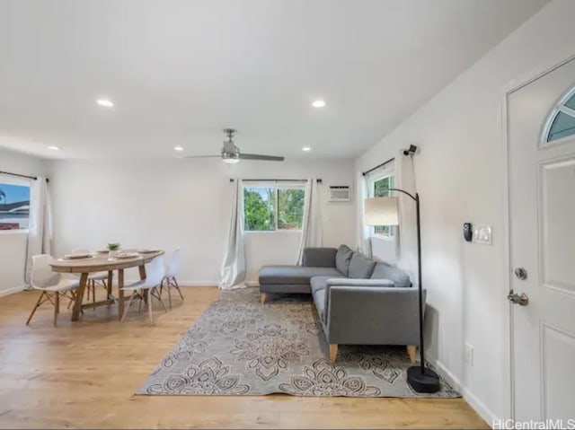 living room featuring a wall unit AC, ceiling fan, and light wood-type flooring