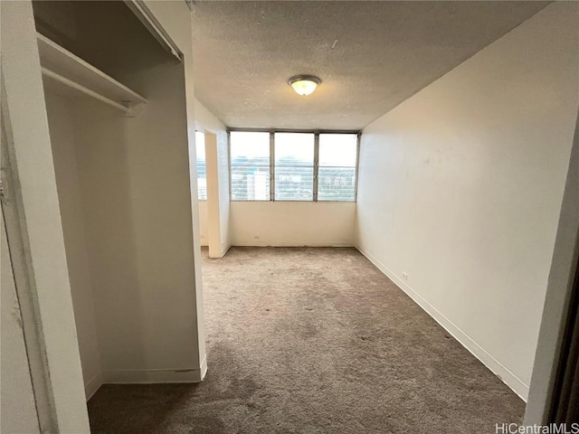 interior space featuring a textured ceiling, carpet floors, and baseboards