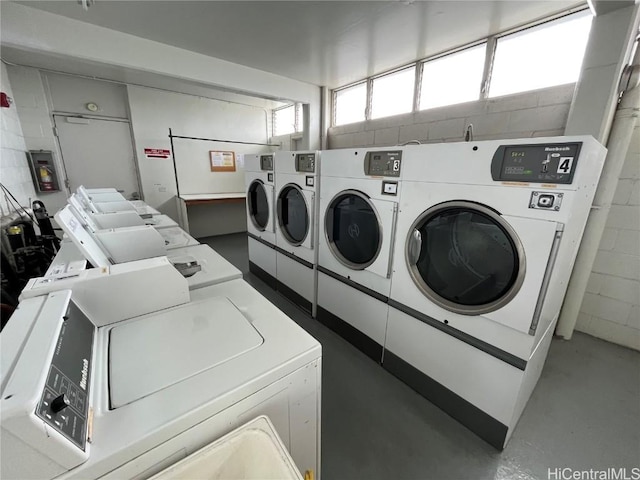 shared laundry area featuring concrete block wall and separate washer and dryer