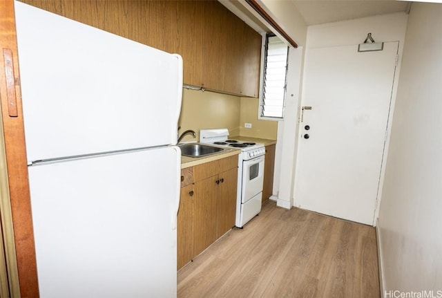 kitchen featuring light countertops, white appliances, a sink, and light wood-style flooring