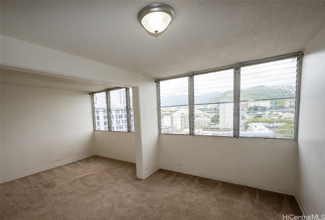 spare room with a textured ceiling, baseboards, and light colored carpet