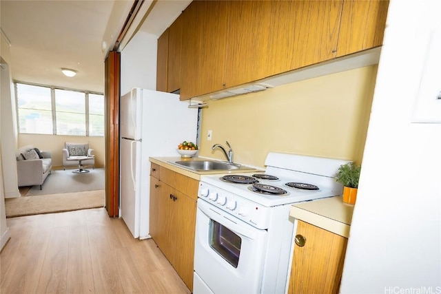 kitchen featuring light wood-style floors, white appliances, light countertops, and a sink