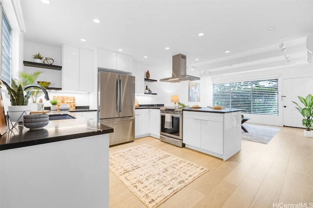 kitchen featuring island exhaust hood, kitchen peninsula, stainless steel appliances, white cabinets, and light hardwood / wood-style floors