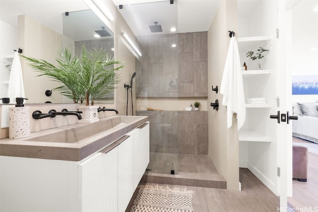 bathroom with hardwood / wood-style flooring, vanity, and a tile shower