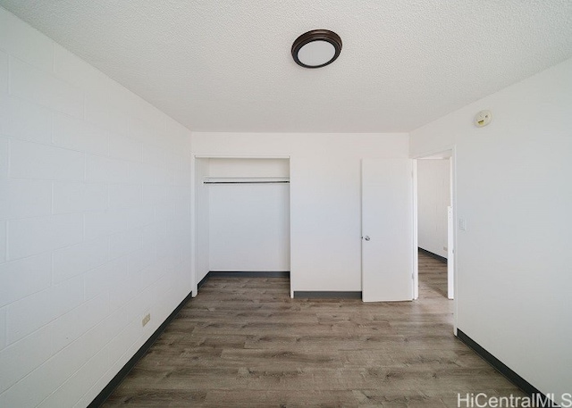 unfurnished bedroom featuring a textured ceiling, a closet, and dark wood-type flooring