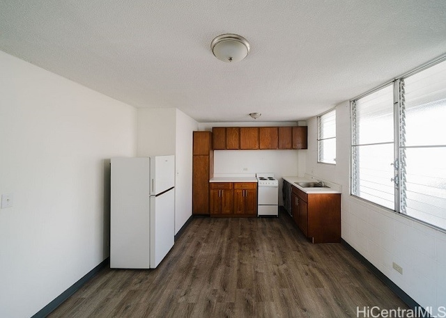 kitchen featuring a textured ceiling, sink, white appliances, and dark wood-type flooring