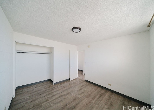 unfurnished bedroom with hardwood / wood-style floors, a textured ceiling, and a closet