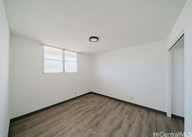 empty room with a textured ceiling and dark hardwood / wood-style floors