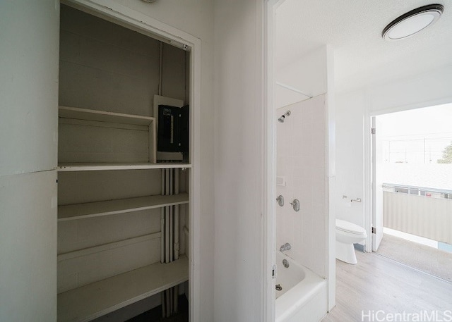 bathroom featuring wood-type flooring,  shower combination, and toilet