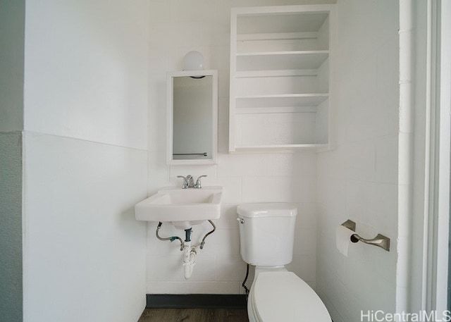 bathroom with hardwood / wood-style floors, toilet, tile walls, and sink