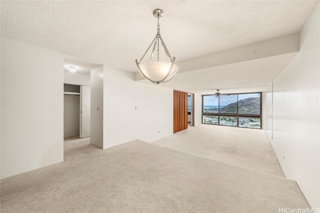 empty room with carpet flooring, ceiling fan, and a textured ceiling