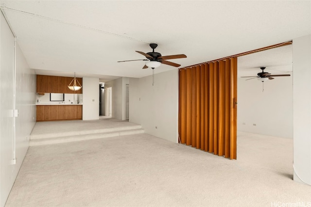 unfurnished living room with light colored carpet and ceiling fan