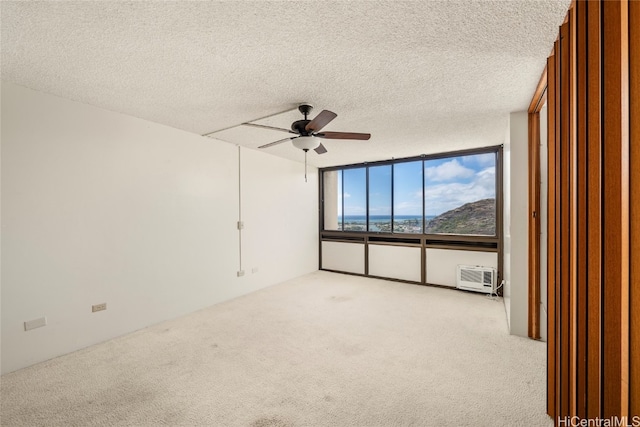 carpeted empty room featuring a textured ceiling, a wall unit AC, and ceiling fan