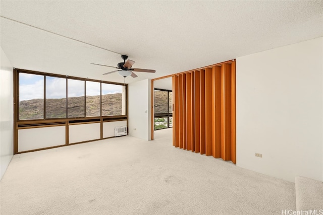 carpeted spare room featuring a mountain view, ceiling fan, a textured ceiling, and a wall mounted AC