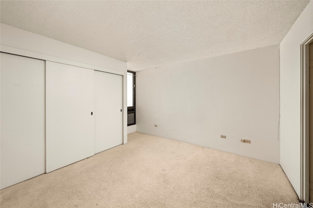 unfurnished bedroom featuring light carpet, a closet, and a textured ceiling