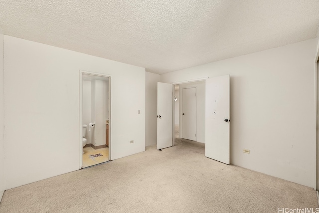 unfurnished bedroom featuring a textured ceiling, light carpet, and connected bathroom