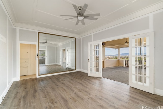 empty room featuring crown molding, french doors, ceiling fan, and wood-type flooring