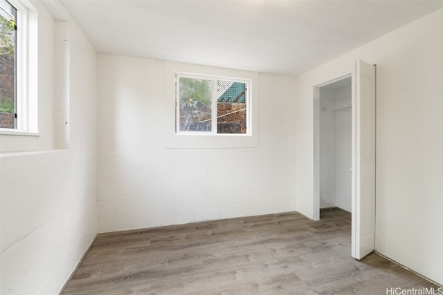 unfurnished bedroom with a closet, light hardwood / wood-style flooring, and multiple windows