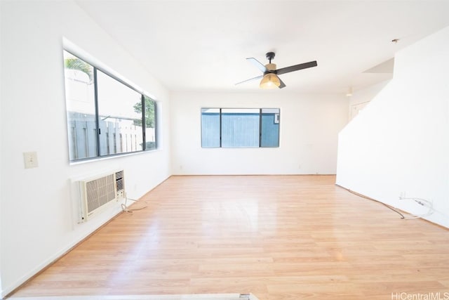 empty room featuring ceiling fan, a wall unit AC, and light wood-type flooring